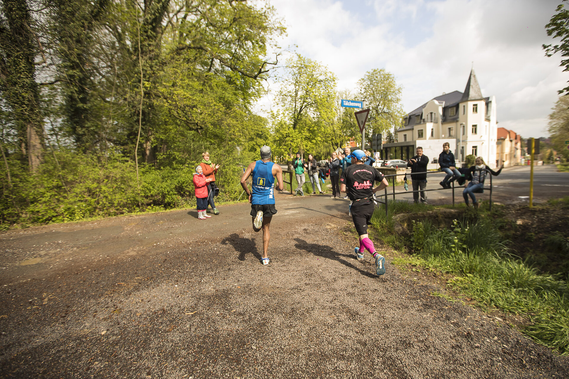 Goethe-Kultur-Lauf Anmeldung: 7,7 km Strecke – 2 Teilnehmer laufen auf einem Schotterweg den Zuschauern entgegen und werden von diesen angefeuert © SCC EVENTS / Tom Wenig